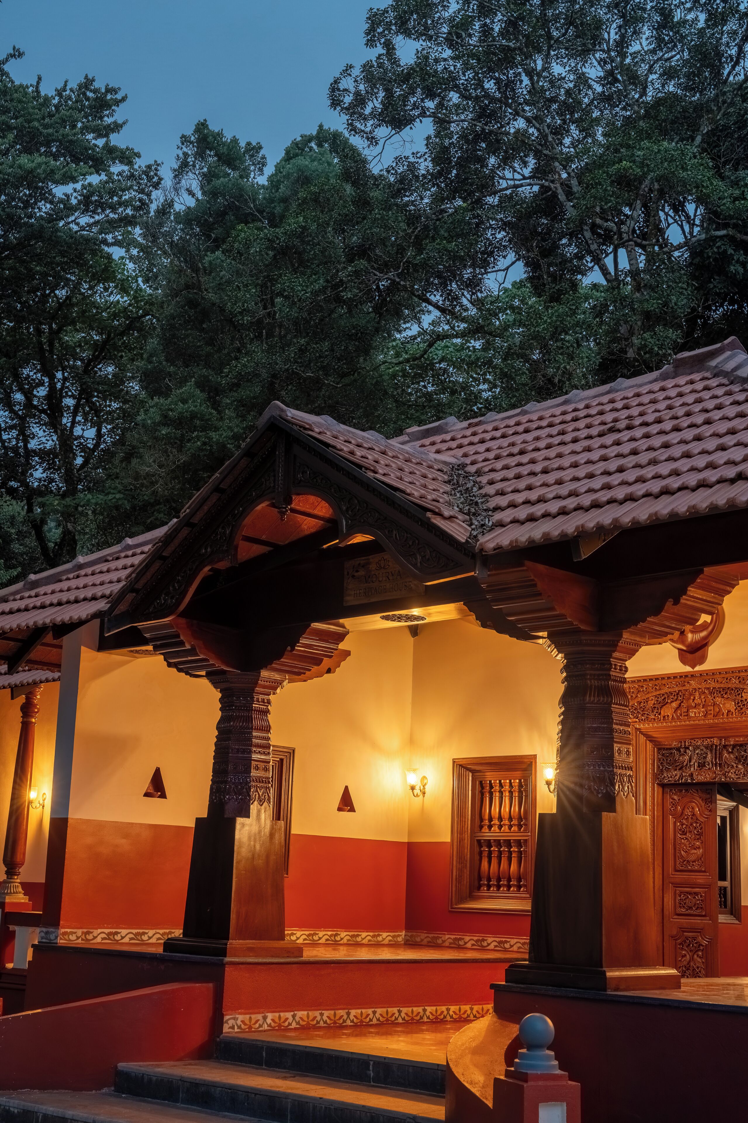 A traditional building with a tiled roof, wooden columns, and a staircase leading to an entrance.