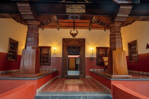 Une entrée traditionnelle en bois, sur laquelle est apposée une plaque indiquant : « MAISON MURYA, PATRIMOINE ».