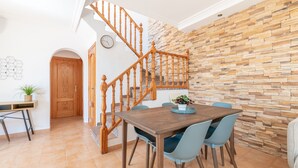 Un comedor con una escalera de madera, pared de piedra y un reloj en la pared.