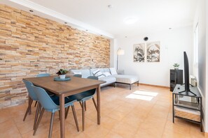 Una sala de estar moderna con una pared de piedra, una mesa de comedor con sillas, un sofá, un mueble para televisor y obras de arte en la pared.