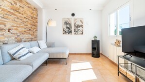 Una sala de estar moderna con un sofá seccional, un televisor de pantalla plana, una chimenea y un ventanal grande.