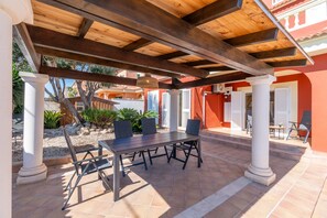 Un patio al aire libre con una pérgola de madera, una mesa y sillas.