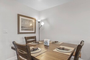 A dining area with a wooden table, four chairs, a framed picture on the wall, and a floor lamp. - Heavenly Condo | Walk to Lift | Balcony | Sleeps 6 (Stateline)