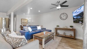 A living room with a blue sofa, a wooden coffee table, a clock, and a ceiling fan. - Heavenly Condo | Walk to Lift | Balcony | Sleeps 6 (Stateline)