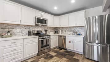 A modern kitchen with white cabinetry, stainless steel appliances, and a patterned backsplash.