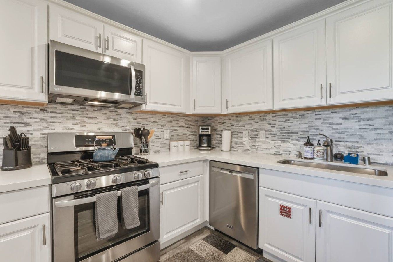 A modern kitchen with white cabinetry, stainless steel appliances, a microwave, stove, oven, and dishwasher.