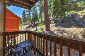 A wooden deck with a table and chairs, overlooking a forested area with rocks and trees. - Heavenly Condo | Walk to Lift | Balcony | Sleeps 6 (Stateline)