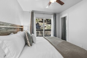 A bedroom with a bed, a ceiling fan, and a view of the outdoors through a door.