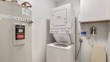 A compact laundry room with a front-loading washing machine and a dryer, a water heater, and a water meter.