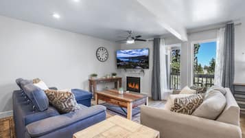 A living room with a fireplace, a television, and a clock on the wall.
