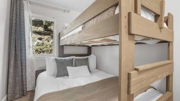 A bunk bed with a wooden frame and white bedding.