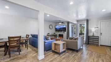 A living room with a fireplace, sofas, a TV, and a dining area with chairs and a table.
