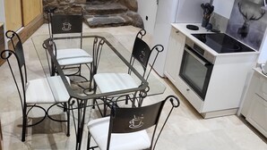 A compact kitchen with a dining area, a stone wall, and a view of a forest. - Cosy and comfortable 3* village house (Dorres)