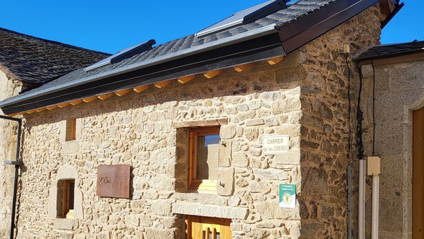 A stone building with a wooden door, a window, and a sign indicating 'CARRER de les CIRERES'. - Cosy and comfortable 3* village house (Dorres)
