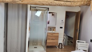 A modern bathroom with a glass shower enclosure, wooden vanity, and a white sink. - Cosy and comfortable 3* village house (Dorres)