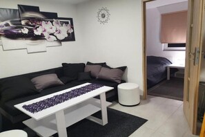 Un salon moderne avec un canapé noir, une table basse blanche et un élément décoratif mural.