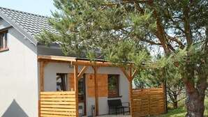 A single-story building with a covered porch, a small patio, and a wooden fence.
