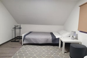 Una habitación pequeña con una cama individual, una mesita de noche con lámpara y un radiador.