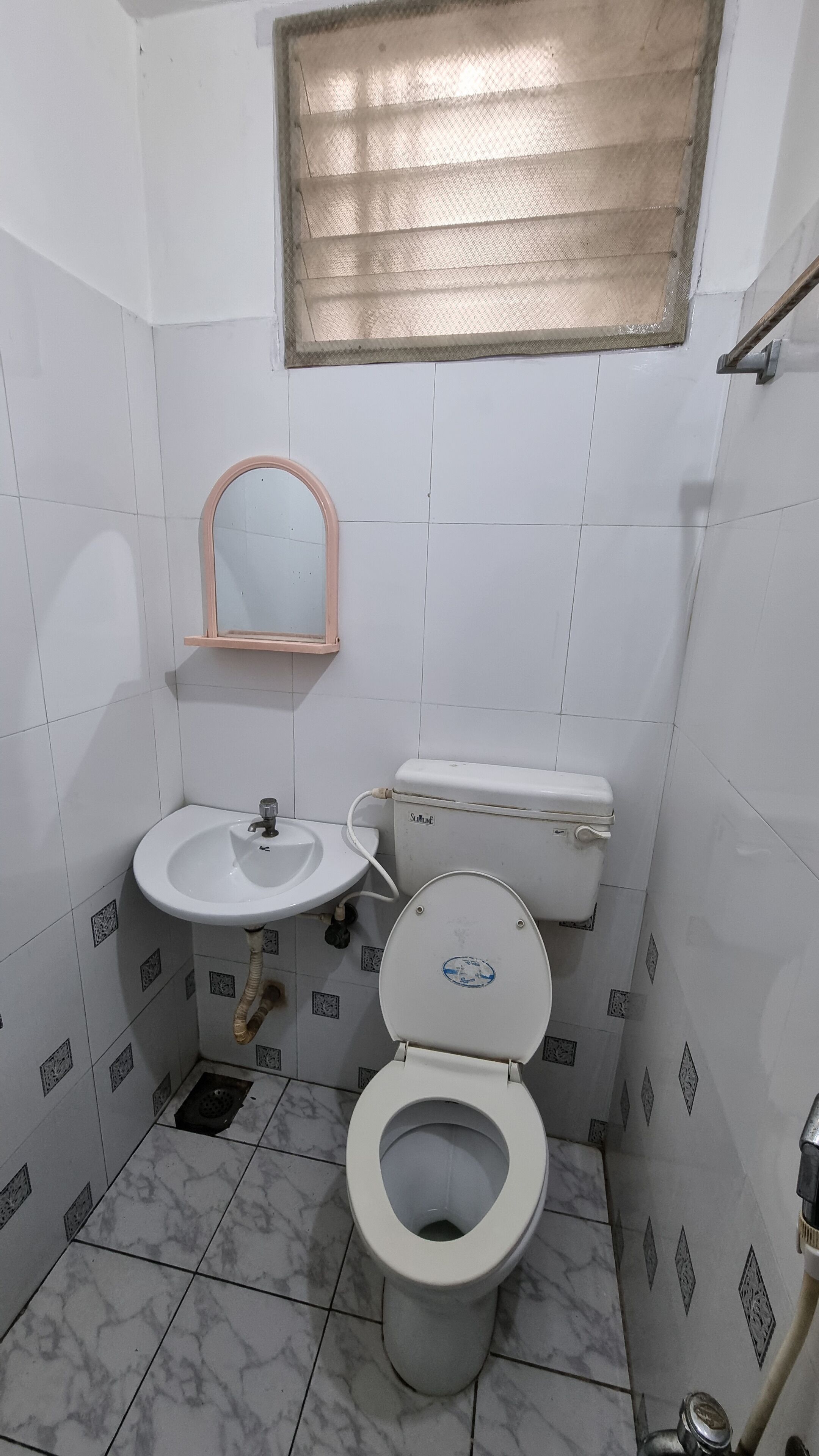 Um banheiro pequeno com azulejos, incluindo vaso sanitário, pia e uma janela sobre a pia.