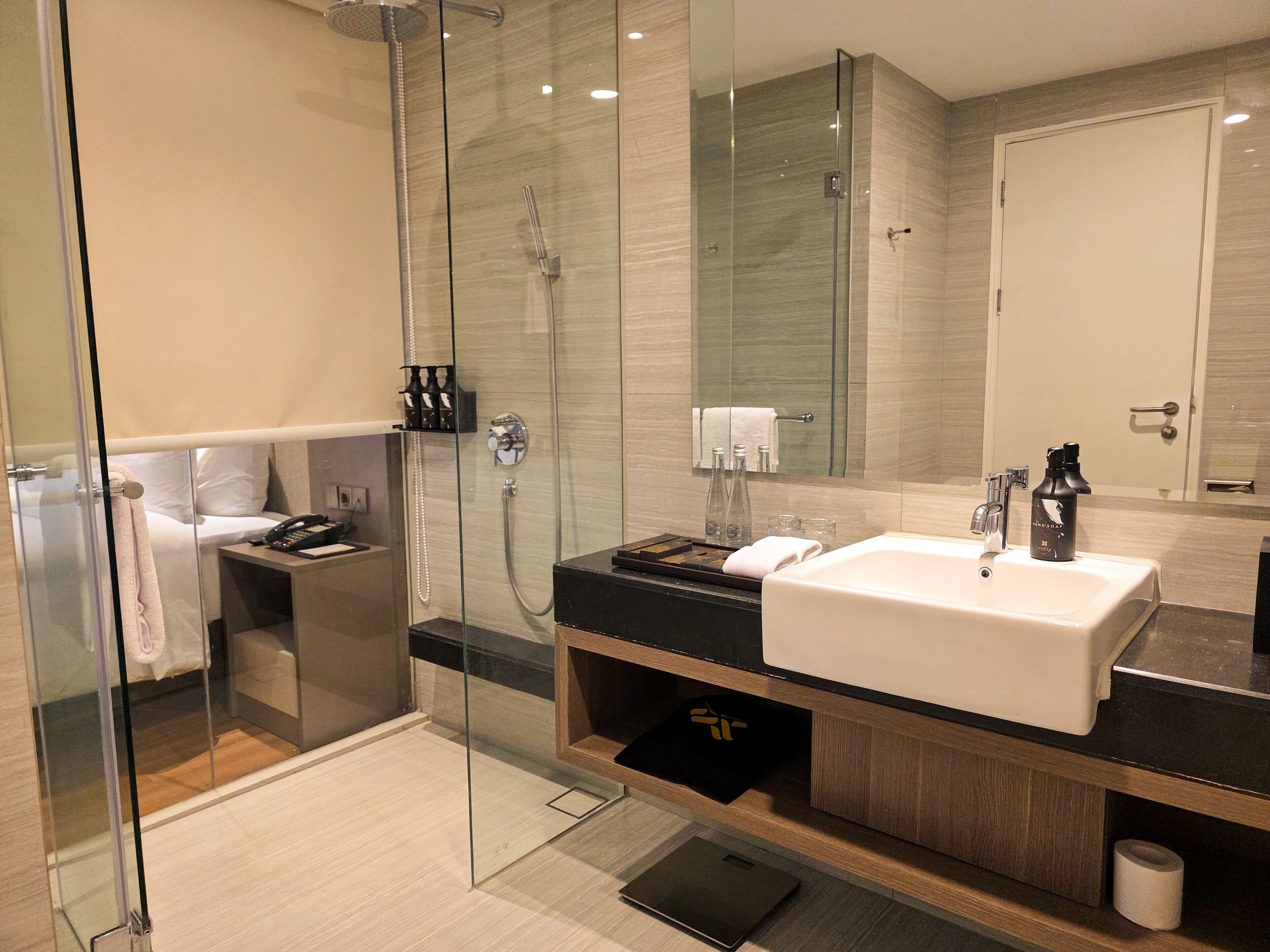 A modern bathroom with a glass-enclosed shower, a large mirror, and a black countertop with a white sink.