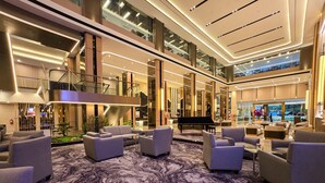 A spacious lobby with a grand piano, plush seating, and a marble floor.