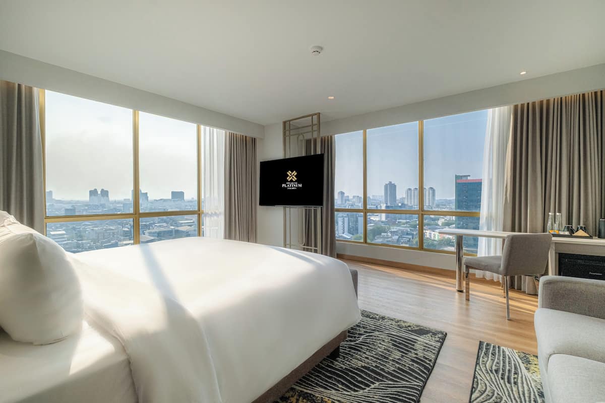 A modern hotel room with a large bed, a desk, and a TV.