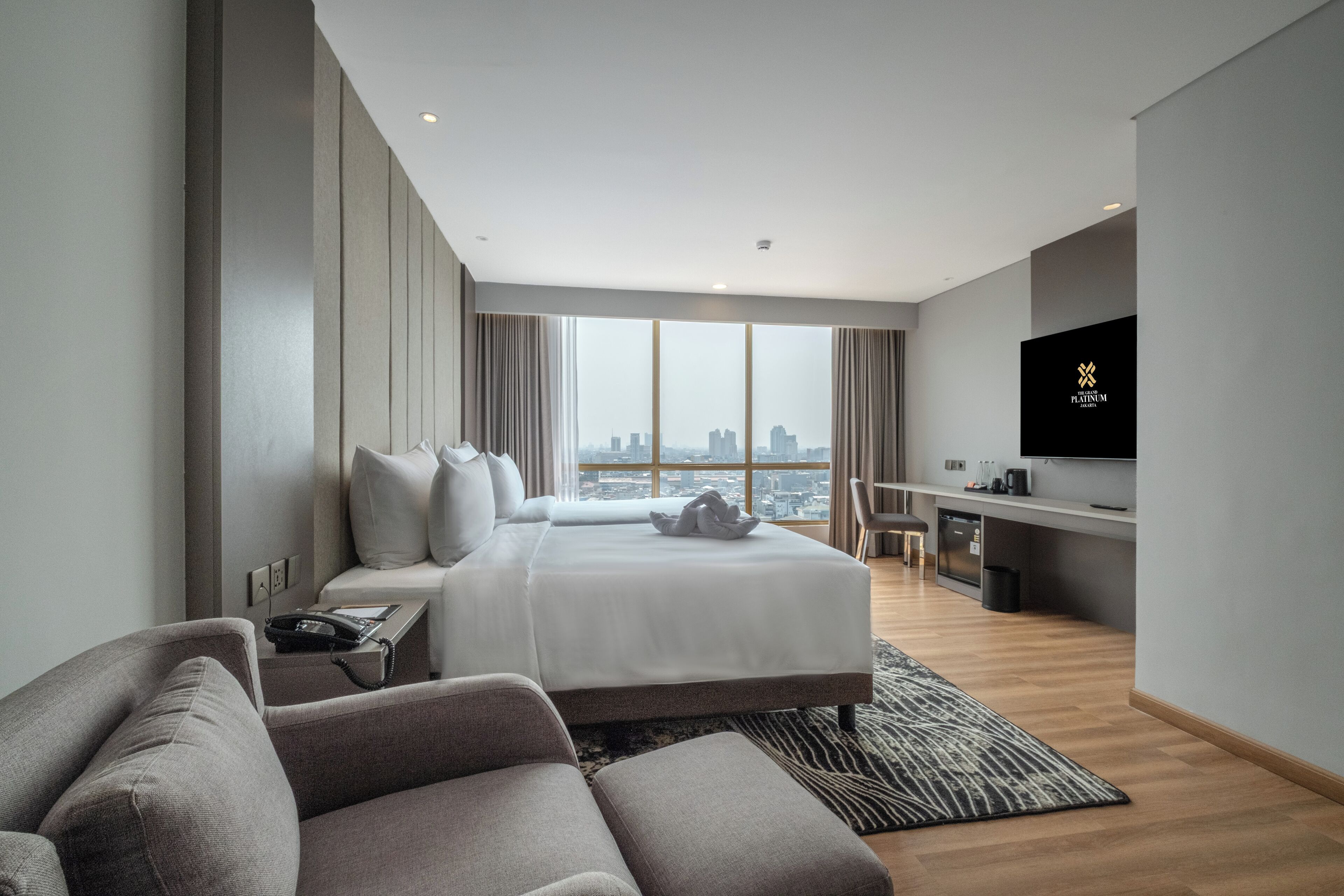 Una habitación de hotel moderna con una cama grande, un escritorio, televisión y vistas a la ciudad.
