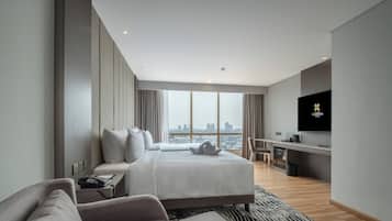 Una habitación de hotel moderna con una cama grande, un escritorio, televisión y vistas a la ciudad.