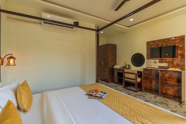 A hotel room with a bed, a desk, a wardrobe, and a television.