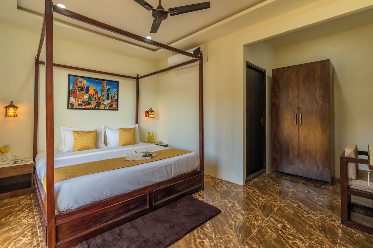 A four-poster bed with a headboard, a painting above it, and a wardrobe to the right.