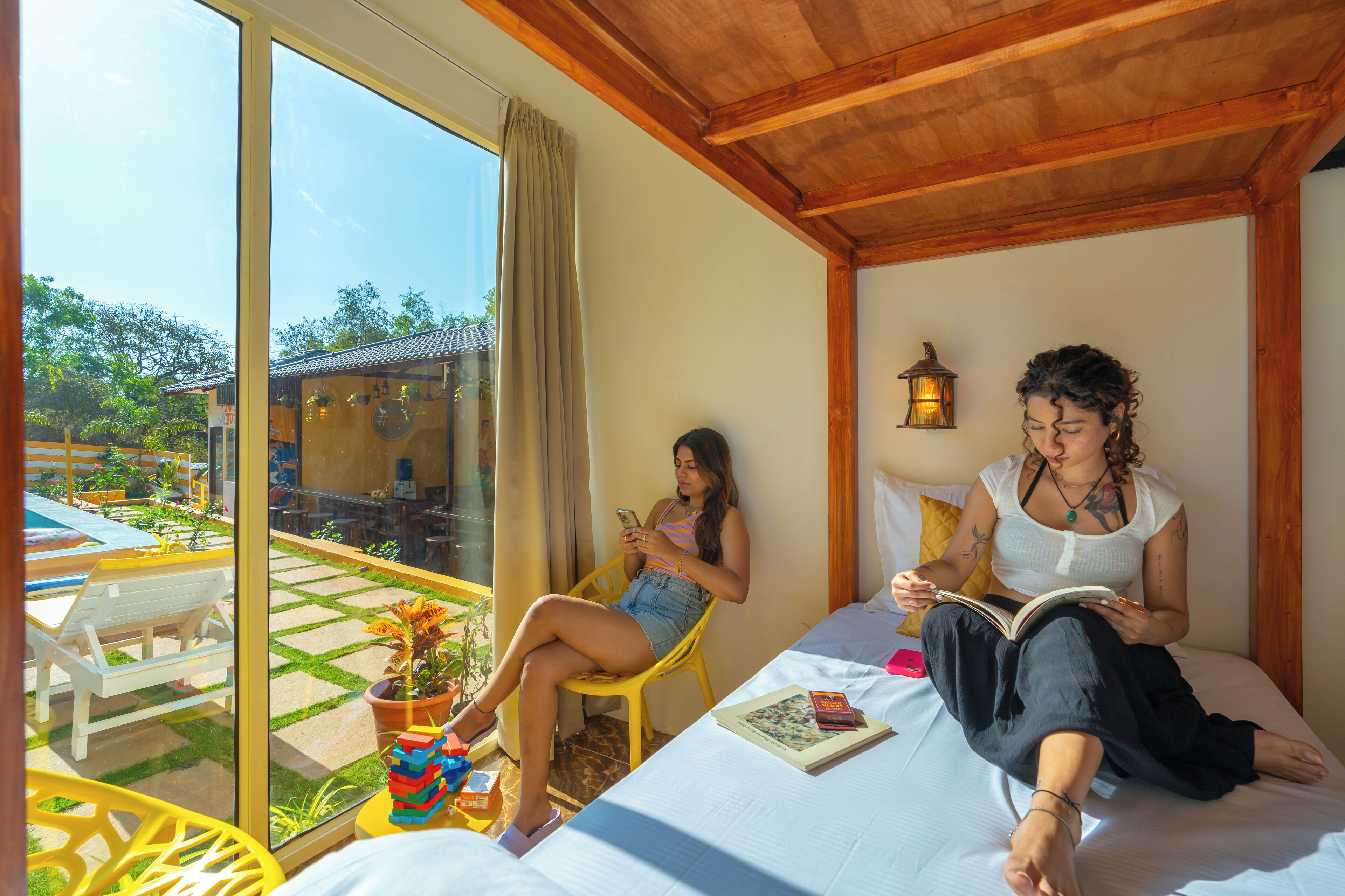 Una habitación con cama, ventana con vistas a un jardín y balcón con mobiliario exterior.
