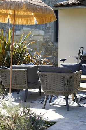 An outdoor seating area with wicker chairs and a thatched umbrella.
