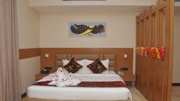 A hotel room with a bed, two nightstands, a wall-mounted artwork, and a wooden partition with flowers.