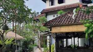 A traditional house with a tiled roof, a thatched-roof structure, and a garden with a paved walkway. - Glam Canggu (Canggu)