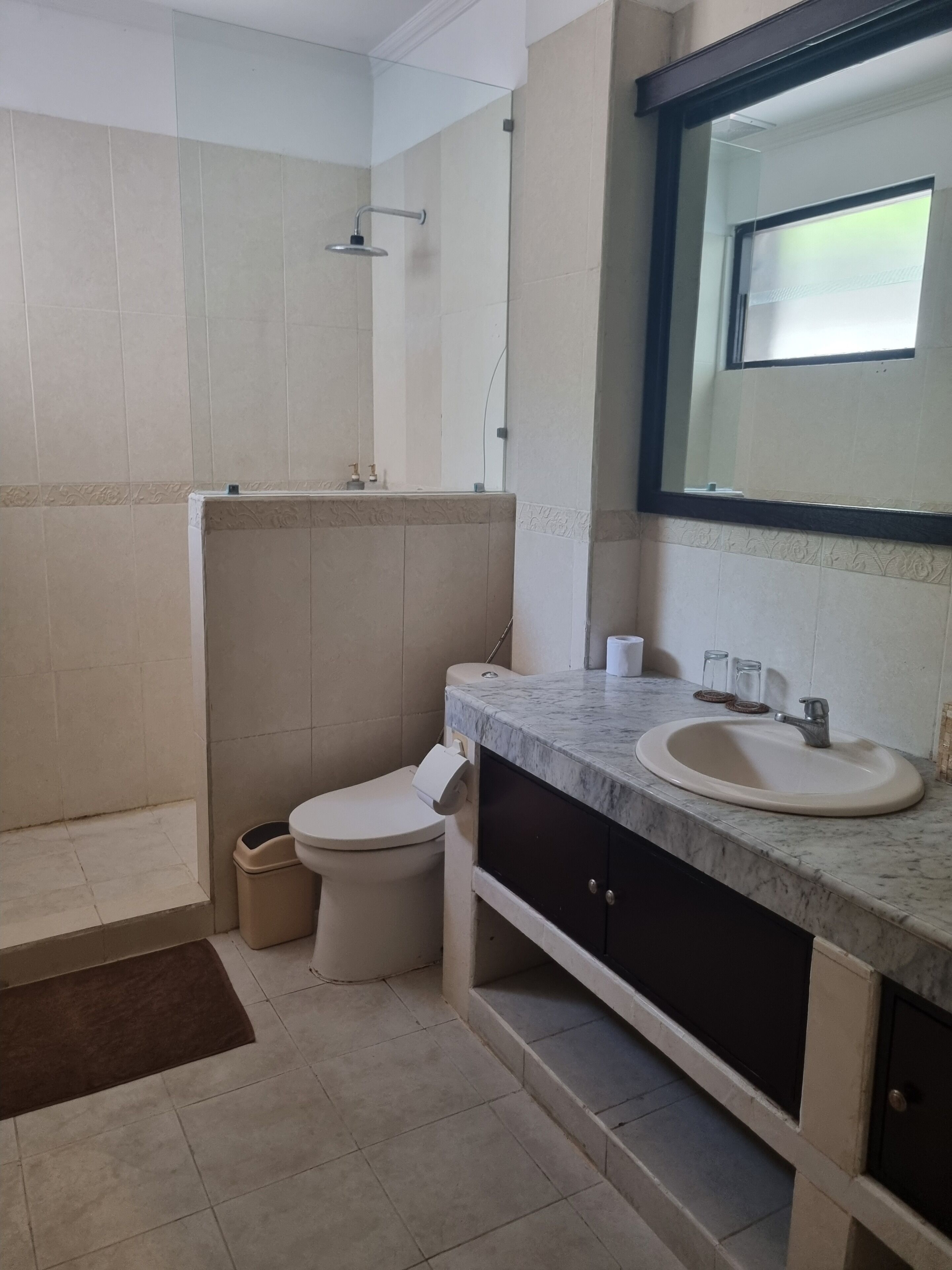 Et badeværelse med toilet, håndvask og bruser.
