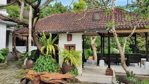A traditional house with a tiled roof, surrounded by lush greenery and a stone pathway. - Glam Canggu (Canggu)