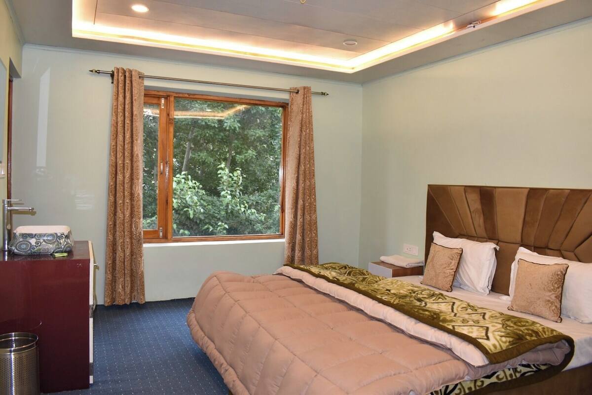 A bedroom with a bed, a nightstand, a dresser, and a window with curtains.