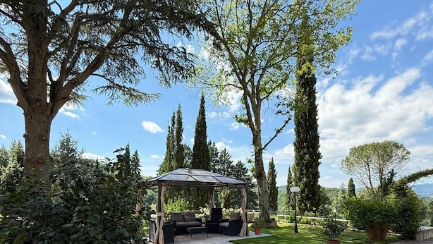 A garden patio with a pergola, seating area, and potted plants. - Charming Guest Room in Villa Casavecchia with Mountain Views (Dicomano)