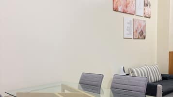 A modern dining area with a glass-top table and grey upholstered chairs.