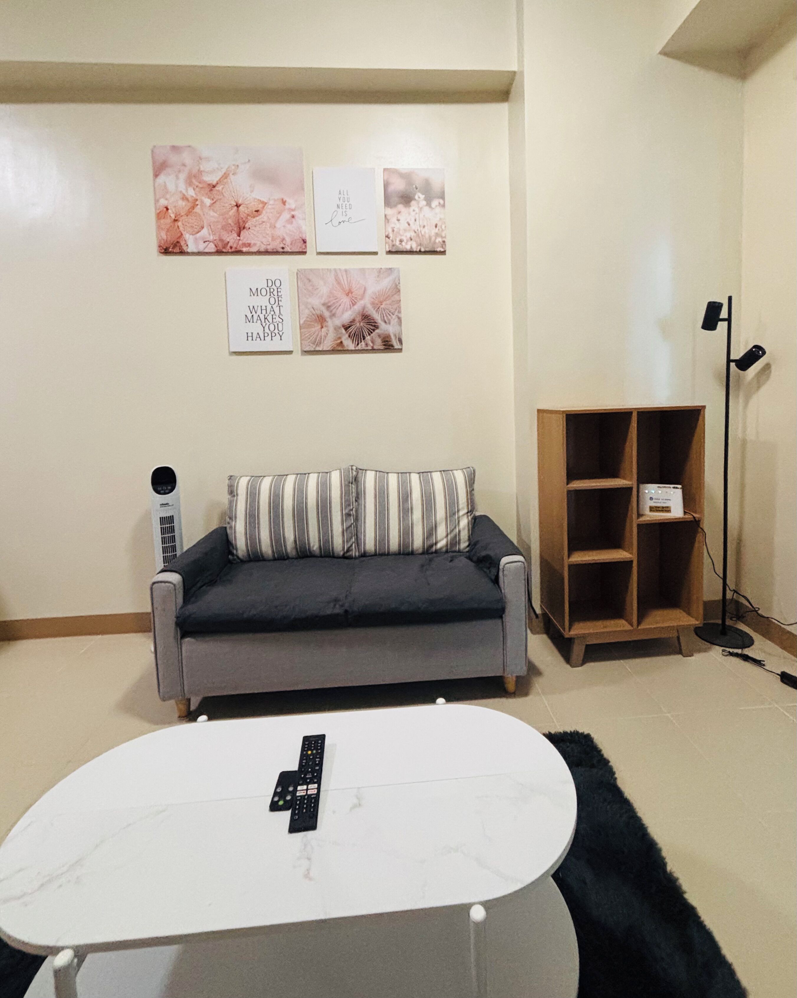 A living room with a grey sofa, a white coffee table, and a black remote control.
