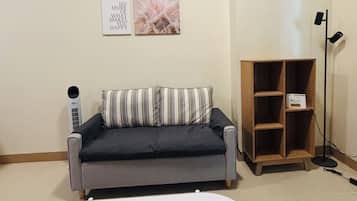 A living room with a grey sofa, a white coffee table, and a black remote control.