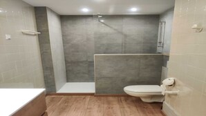 A modern bathroom with a shower, toilet, and a bathtub. - Modern Mountain Apartment with Balcony (Chamrousse)