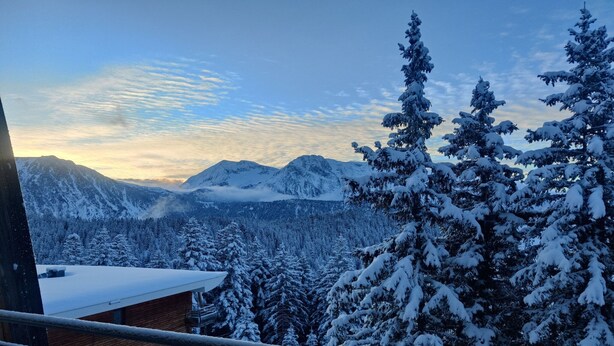 A mountain landscape with snow-covered trees and a wooden cabin. - Modern Mountain Apartment with Balcony (Chamrousse)
