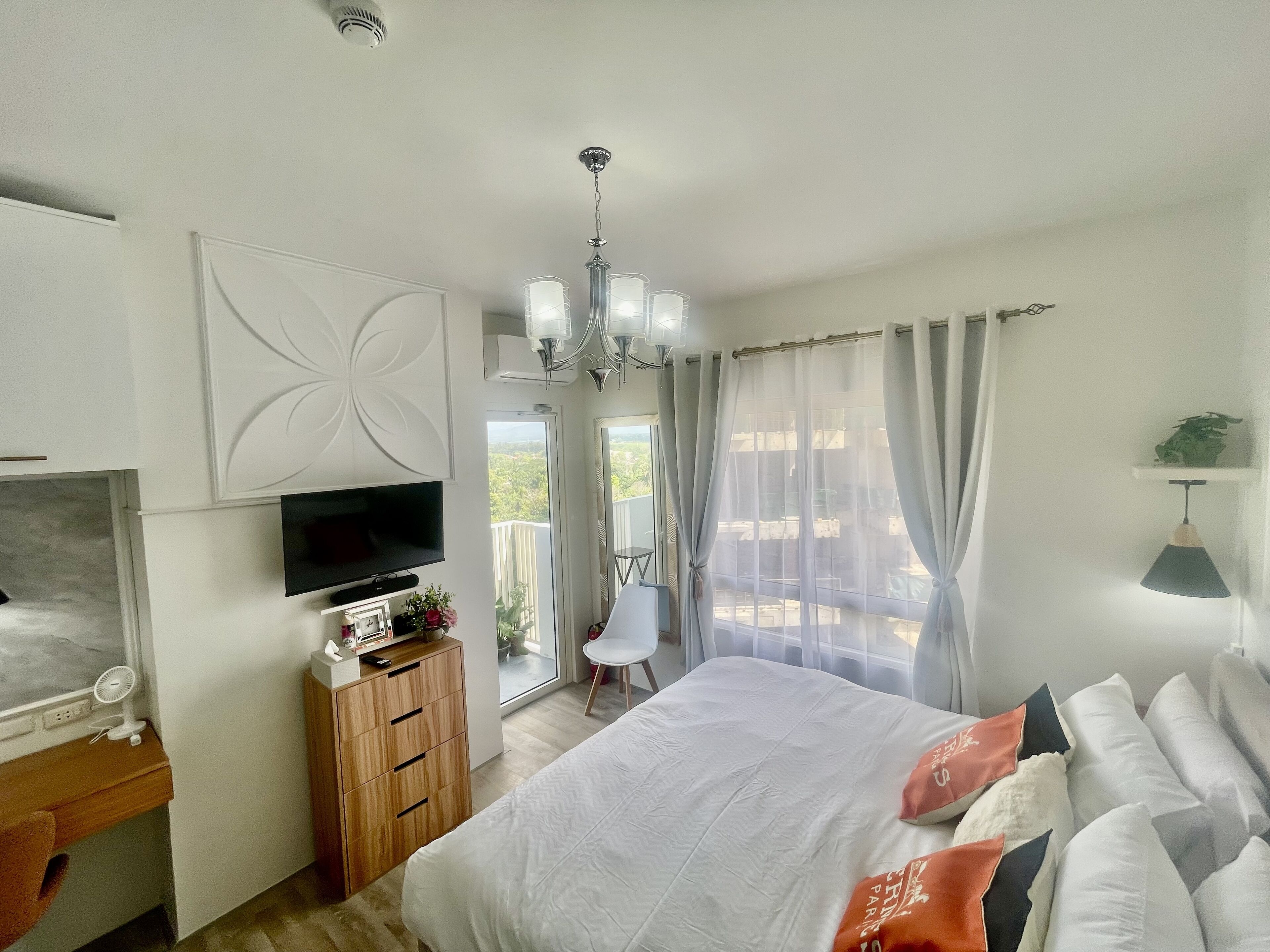 A bedroom with a bed, a TV, a desk, and a chair.