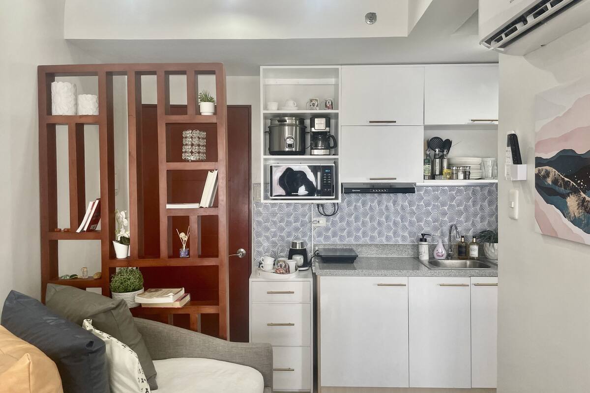 A compact living space with a kitchenette, a wooden bookshelf, and a sofa.