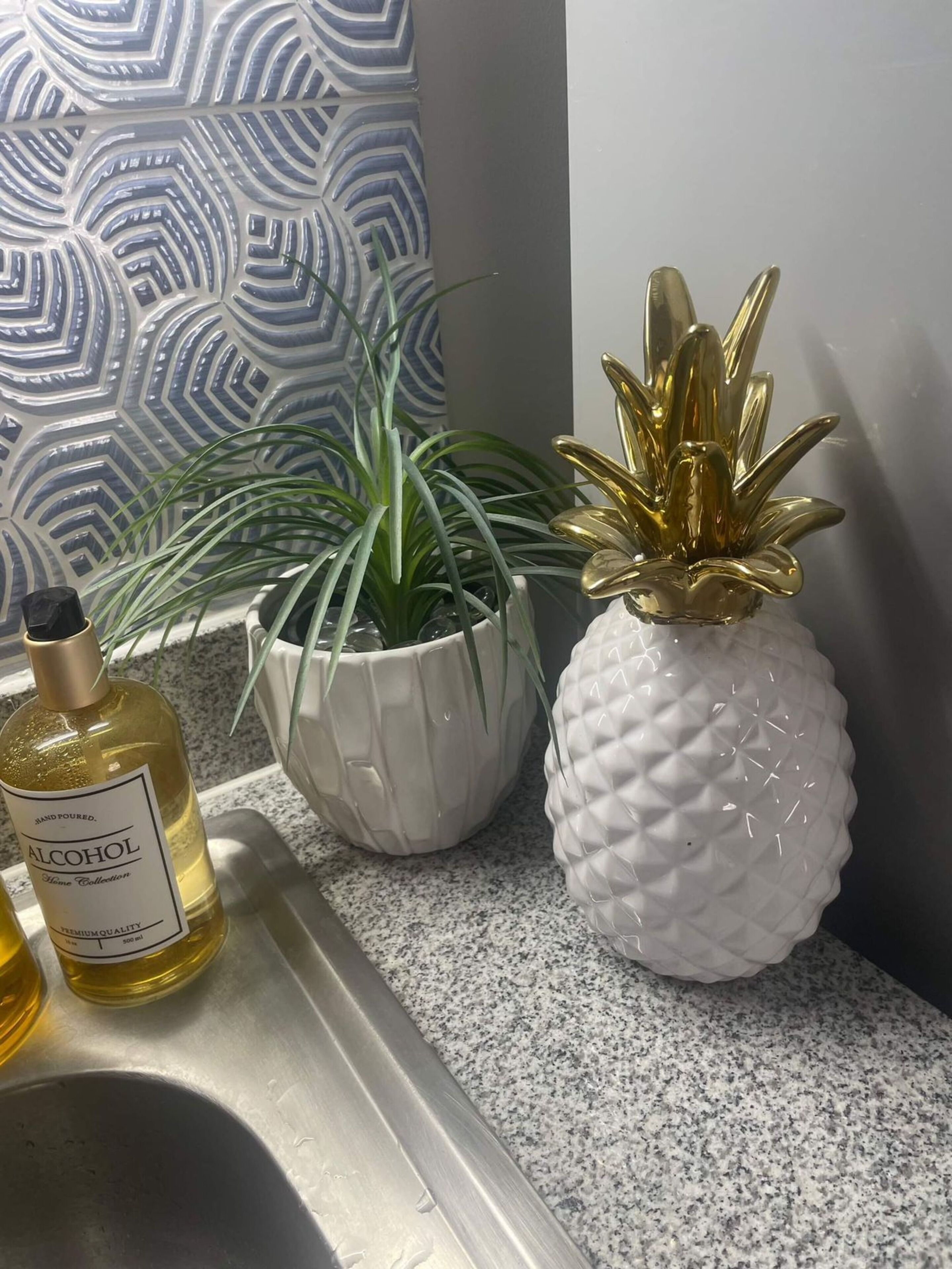 Un piano di lavoro in cucina con una bottiglia di liquore, una pianta in vaso e un'ananas decorativa.
