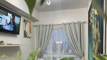Signature Condo, 1 Bedroom, Balcony, City View | Living room | 32-inch Smart TV with cable channels
