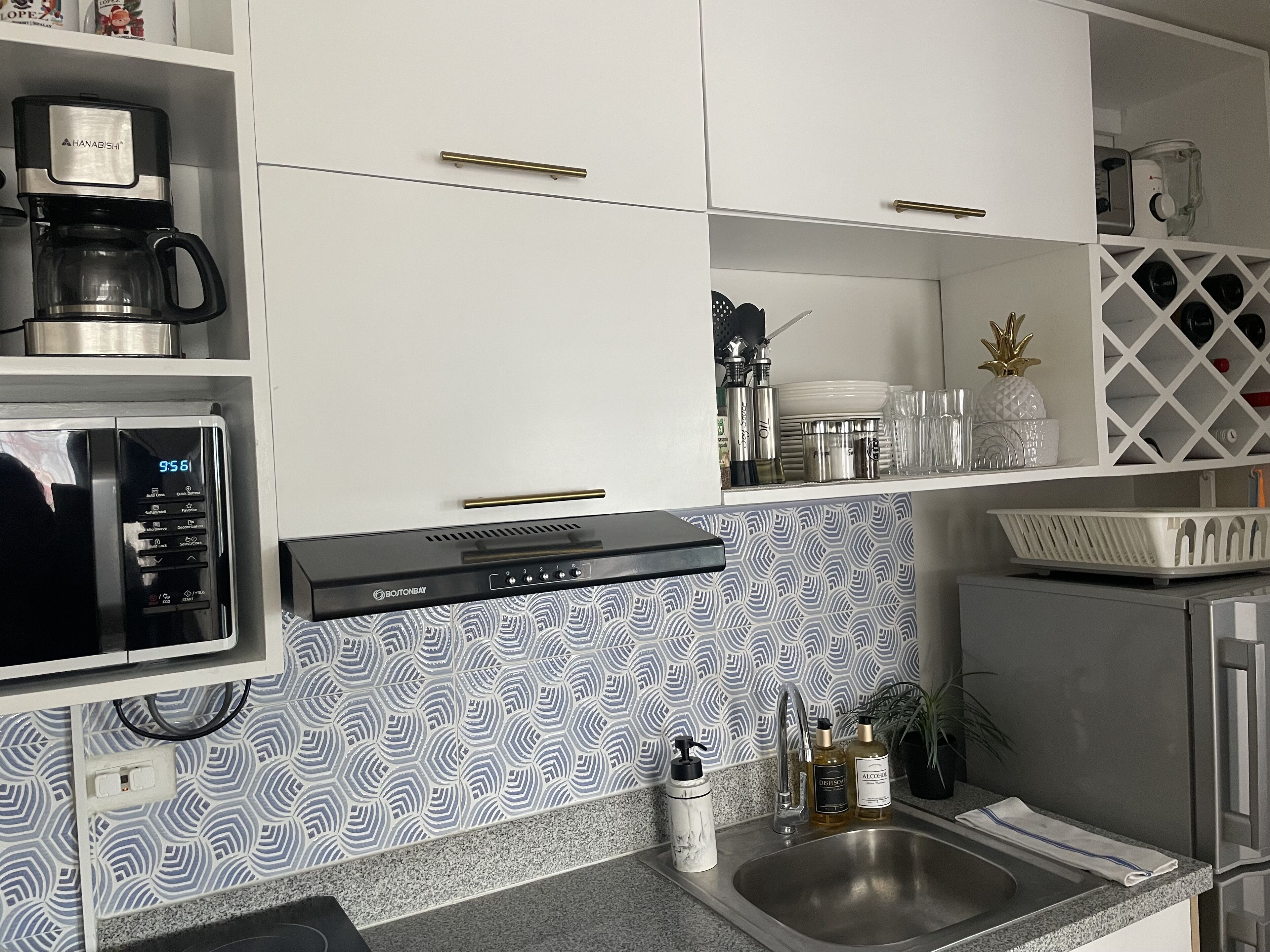 A kitchen with a coffee maker, microwave, and a patterned backsplash.