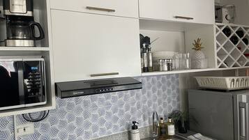 A kitchen with a coffee maker, microwave, and a patterned backsplash.