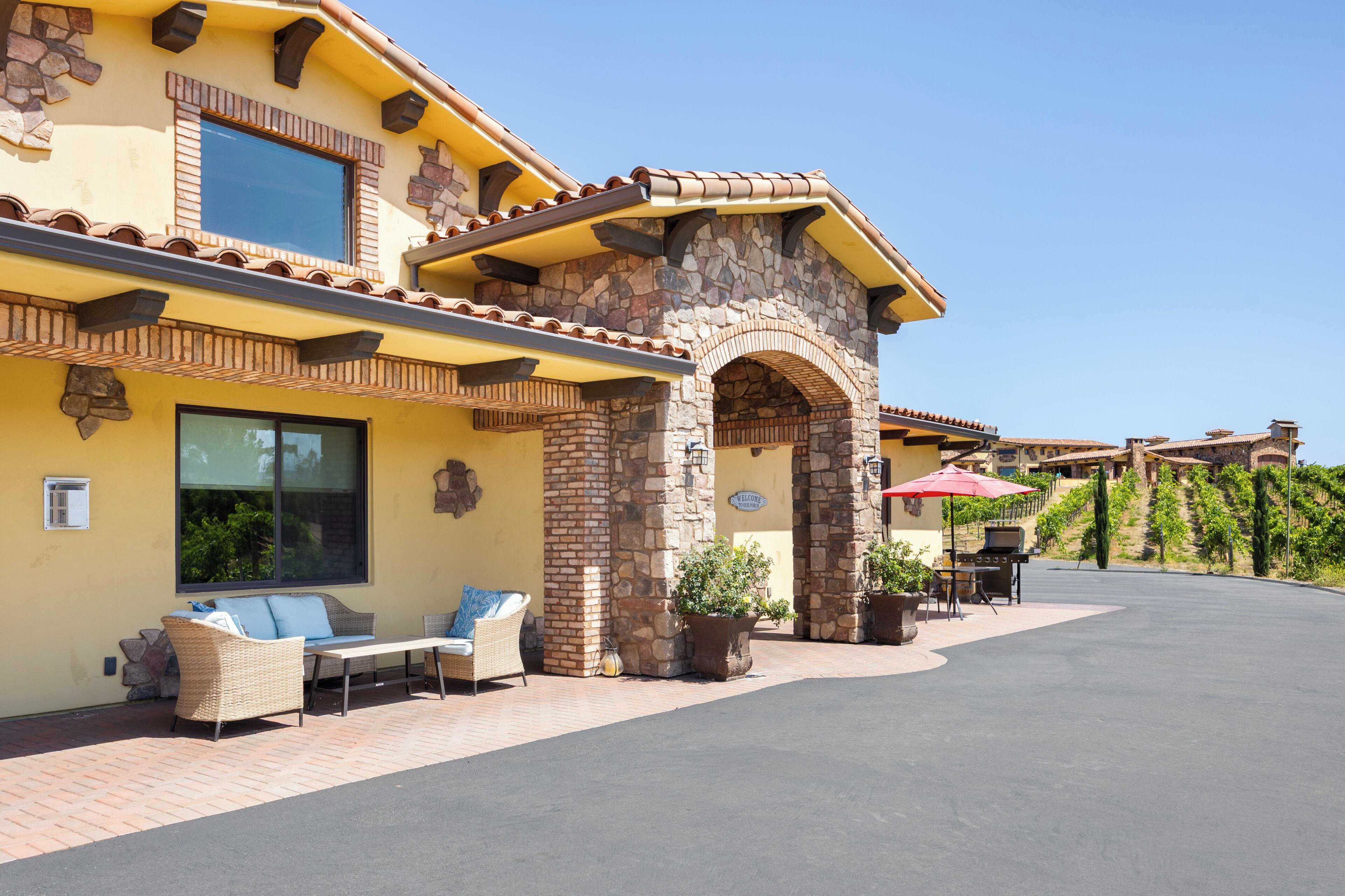 A two-story building with a stone facade, outdoor seating, and a barbecue area.